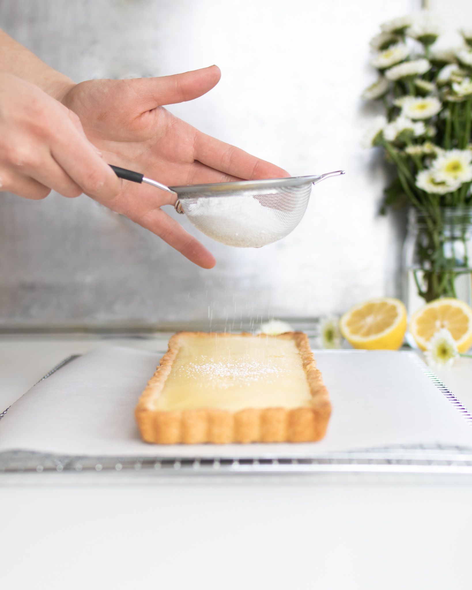 lemon tart being sprinkled with powdered sugar