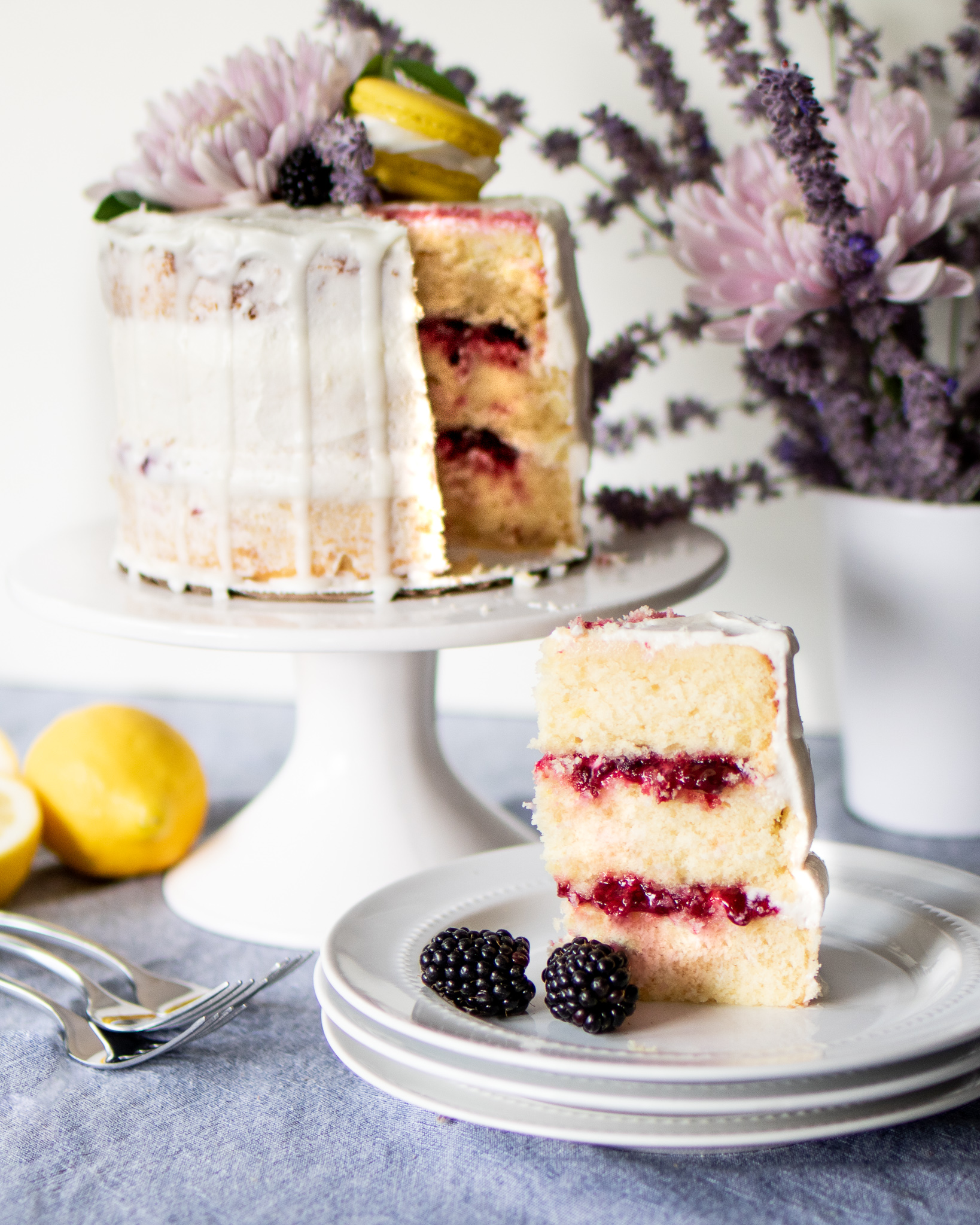 a lemon blackberry cake slice on a plate with the cake in the background