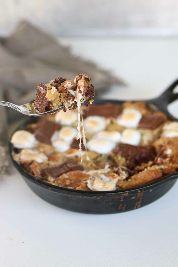 fork lifting out a bite of smores cookies in cast iron pan