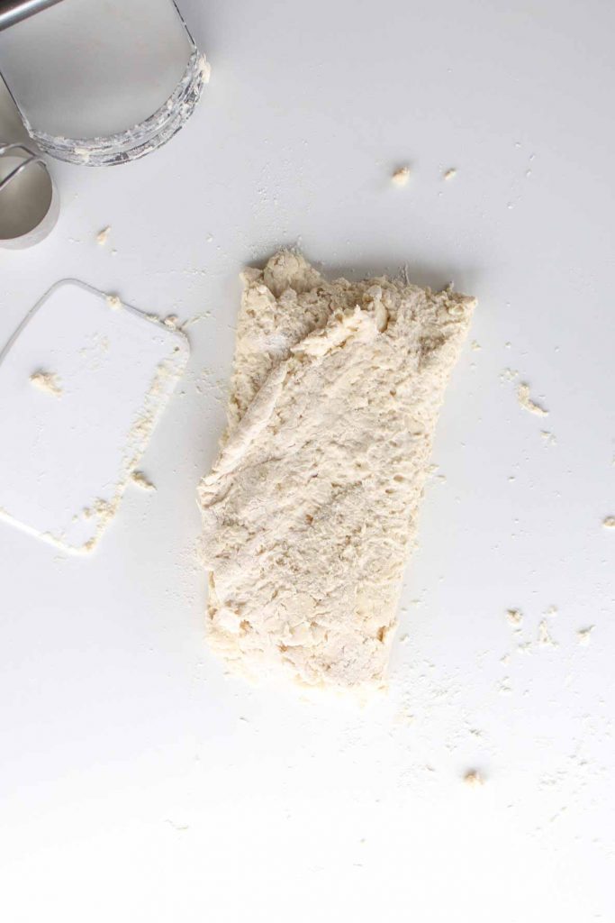 aerial view of folded biscuit dough, pastry cutter, biscuit cutter and bench scraper
