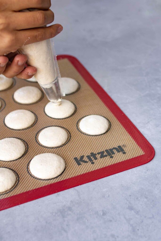 piping macarons onto baking mat